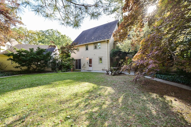 back of property featuring a yard, roof with shingles, and a patio area