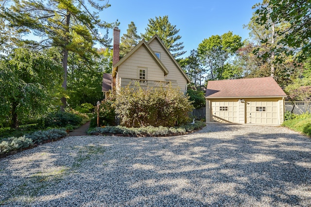 view of side of home with a detached garage, an outdoor structure, and a chimney