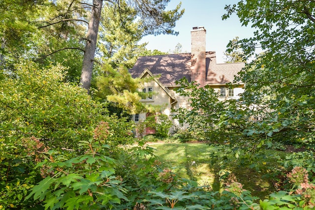 exterior space with roof with shingles, stucco siding, and a chimney