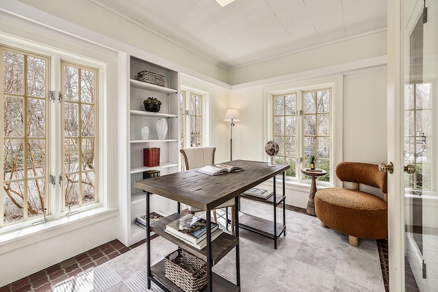 office area featuring brick floor, built in shelves, and a wealth of natural light