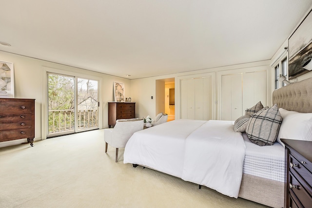 bedroom featuring light colored carpet and multiple closets