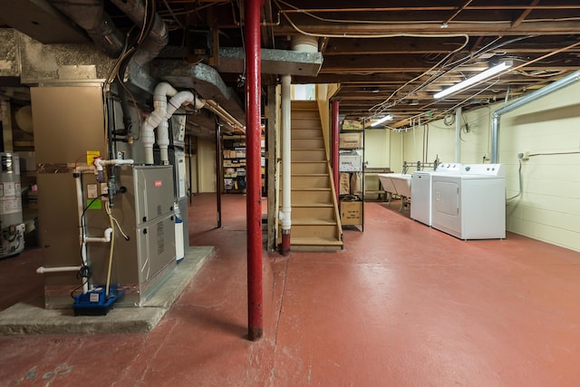 unfinished below grade area with gas water heater, stairway, a sink, heating unit, and washer and clothes dryer