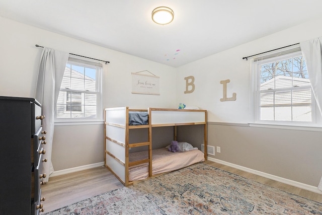 bedroom with wood finished floors, visible vents, and baseboards