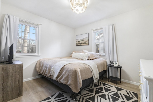 bedroom featuring multiple windows, wood finished floors, and baseboards