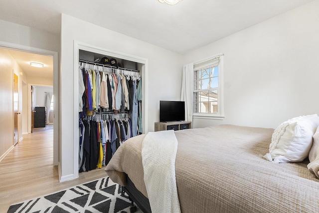 bedroom featuring a closet, baseboards, and light wood finished floors