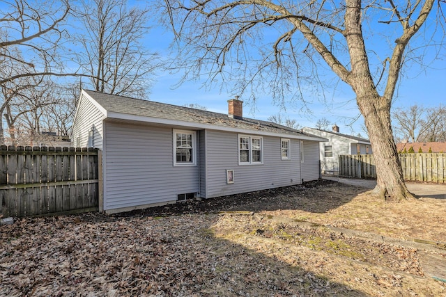 back of property with a chimney and a fenced backyard