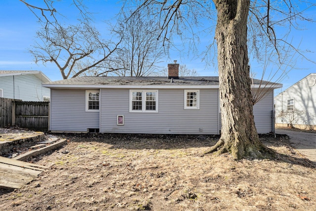 back of property with a chimney and fence