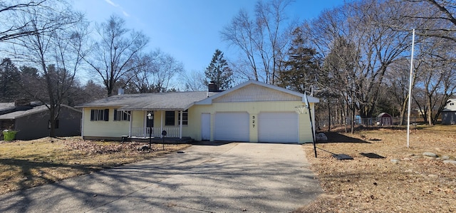 ranch-style house with fence, covered porch, a chimney, a garage, and aphalt driveway