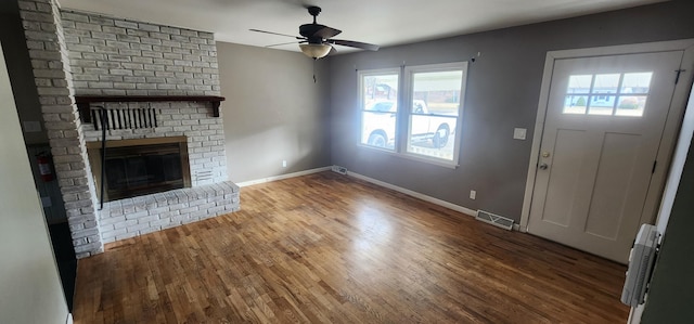 unfurnished living room with wood finished floors, visible vents, baseboards, a fireplace, and ceiling fan