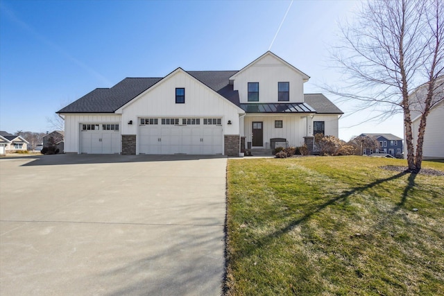 modern farmhouse with a front yard, driveway, a standing seam roof, a garage, and metal roof