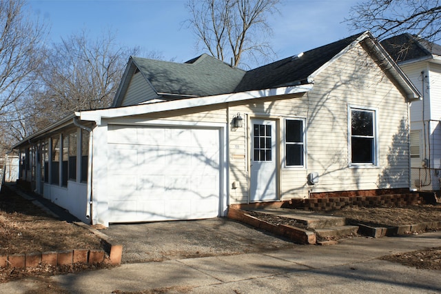 view of property exterior featuring aphalt driveway, roof with shingles, and an attached garage