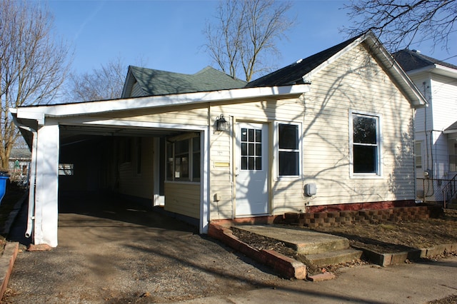 view of side of home with aphalt driveway, a garage, and a shingled roof