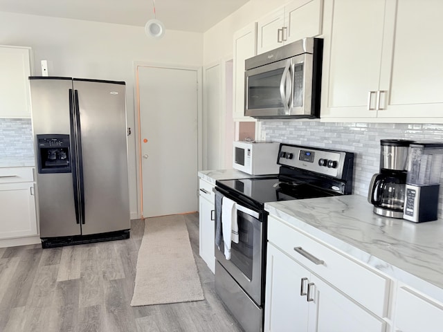 kitchen with light wood-type flooring, backsplash, stainless steel appliances, white cabinets, and light stone countertops