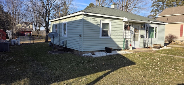 rear view of property with central AC unit, fence, a lawn, and a chimney