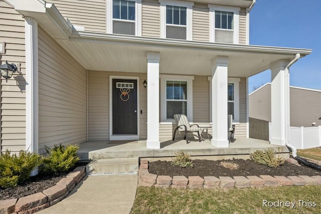 entrance to property featuring covered porch and fence