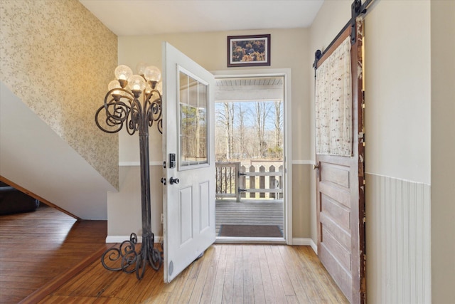 entryway featuring baseboards, a barn door, and wood-type flooring