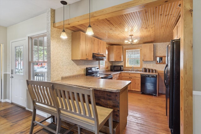 kitchen with a peninsula, black appliances, wood ceiling, under cabinet range hood, and light wood-type flooring