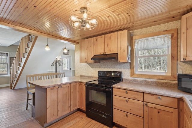 kitchen featuring under cabinet range hood, a peninsula, black appliances, and an inviting chandelier