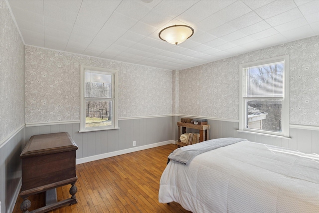 bedroom with wainscoting, wallpapered walls, and wood-type flooring