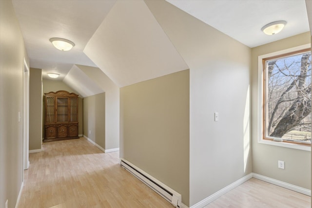 additional living space with a baseboard radiator, plenty of natural light, light wood-style floors, and baseboards