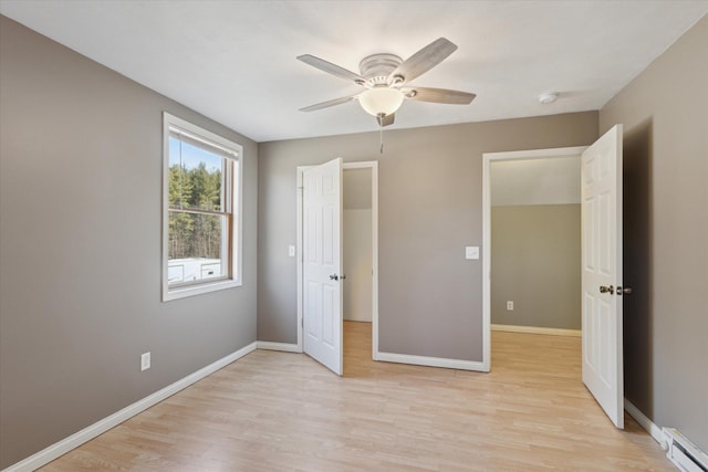 unfurnished bedroom with ceiling fan, baseboards, baseboard heating, and light wood-type flooring