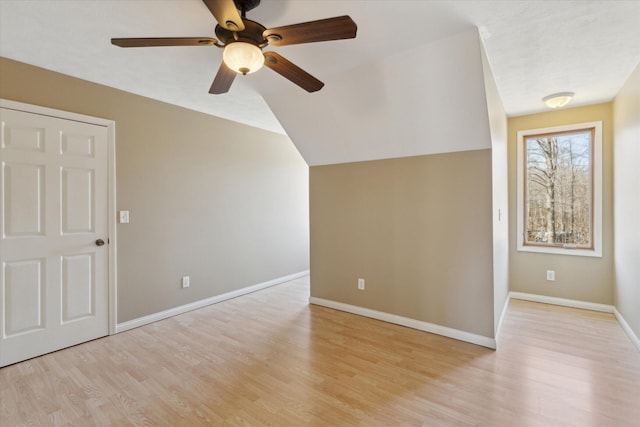 additional living space featuring vaulted ceiling, light wood-style floors, and baseboards