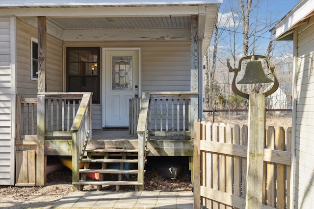 doorway to property with covered porch and fence