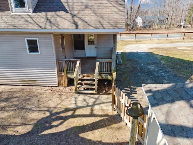 property entrance featuring a shingled roof and fence