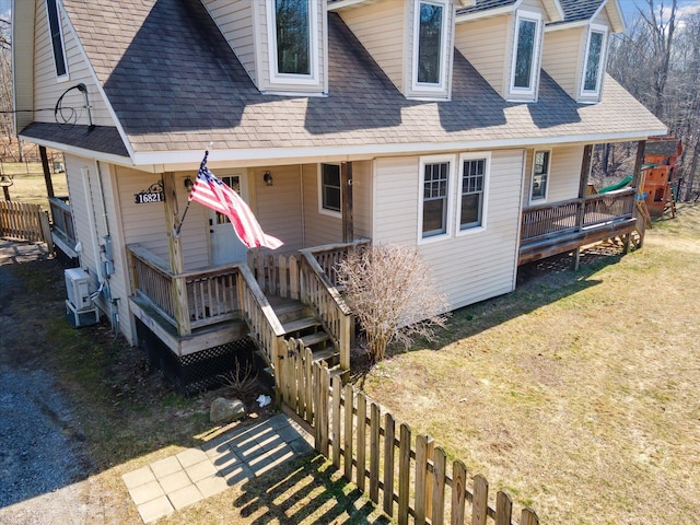 exterior space with a front yard, fence, and roof with shingles