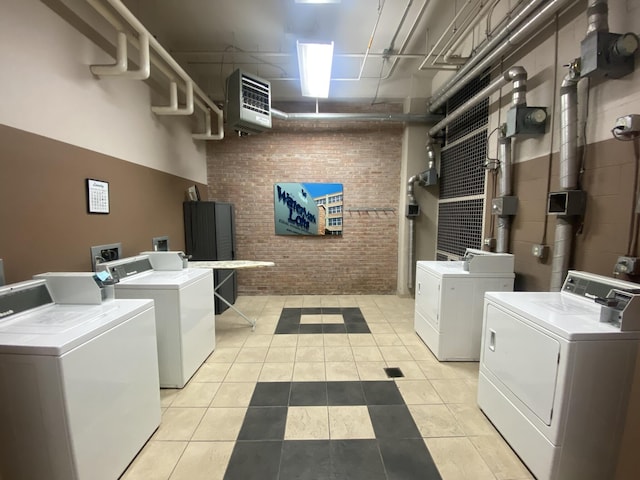 common laundry area featuring light tile patterned flooring, independent washer and dryer, and brick wall