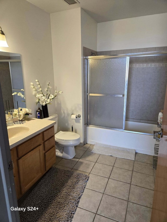 bathroom with enclosed tub / shower combo, toilet, vanity, and tile patterned flooring