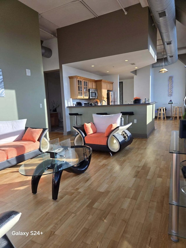 living area with recessed lighting, wood finished floors, and a towering ceiling