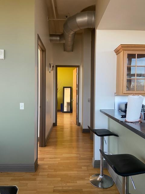 hallway featuring baseboards, a high ceiling, and light wood finished floors