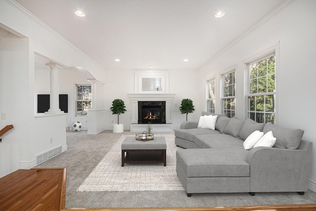 living area with decorative columns, carpet, visible vents, and ornamental molding