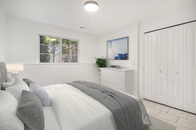 bedroom with visible vents, marble finish floor, and a closet