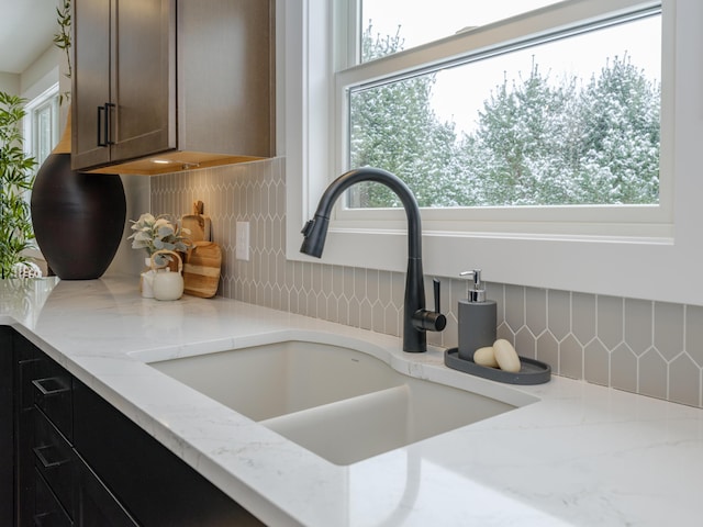 2613 Ashford Trl, Portage, MI 49024 - details featuring decorative backsplash, light stone countertops, and a sink