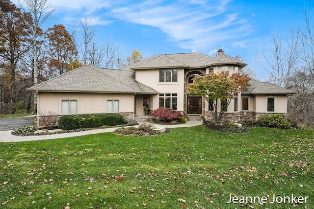 view of front of home featuring stucco siding, stone siding, and a front lawn