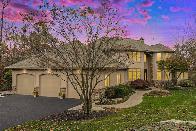 view of front of house featuring aphalt driveway, stone siding, and stucco siding