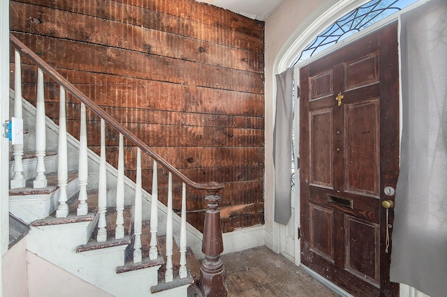 foyer entrance featuring wood walls and stairs