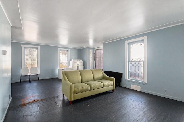 unfurnished living room with dark wood-type flooring, baseboards, ornamental molding, and visible vents