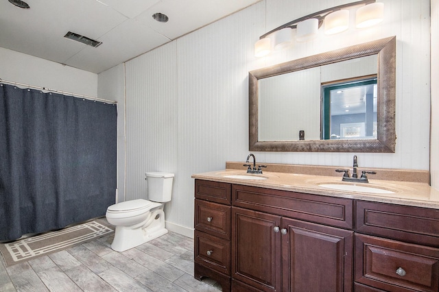 full bathroom featuring toilet, a sink, double vanity, and wood finished floors