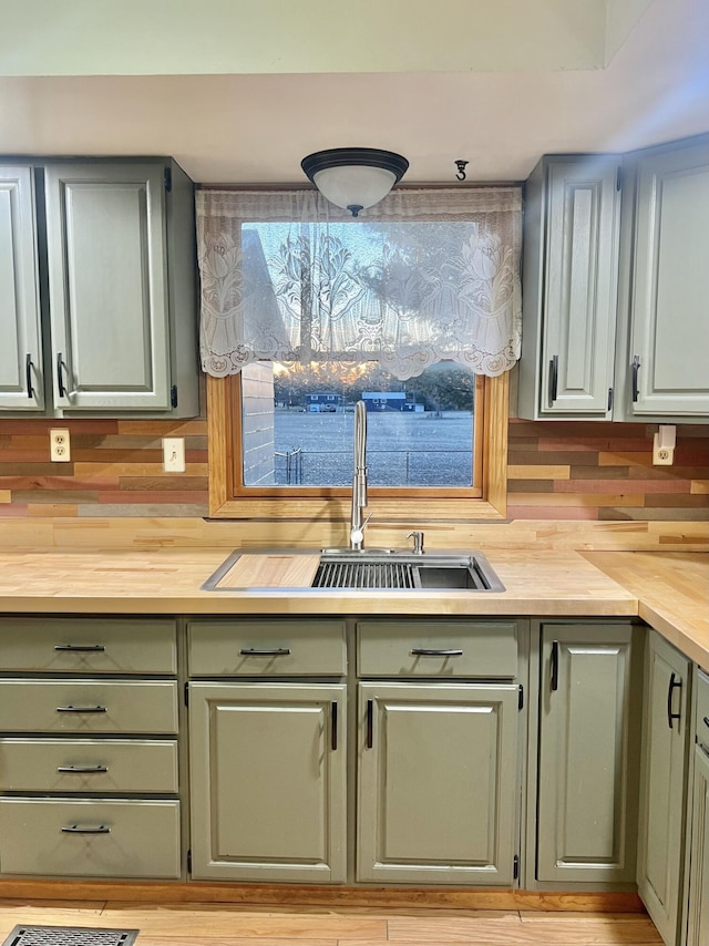 kitchen featuring green cabinetry, wooden counters, and a sink