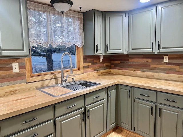 kitchen with gray cabinetry, wooden counters, and a sink