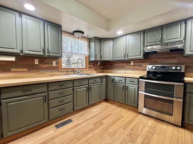 kitchen with double oven range, decorative backsplash, visible vents, gray cabinetry, and under cabinet range hood