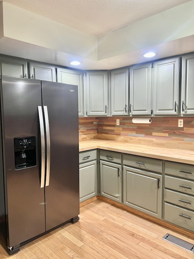 kitchen featuring decorative backsplash, wooden counters, gray cabinetry, light wood-type flooring, and stainless steel refrigerator with ice dispenser