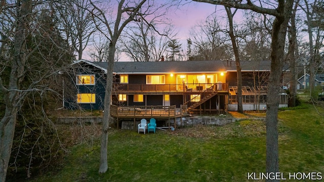 back of property at dusk with a lawn, a wooden deck, and stairs