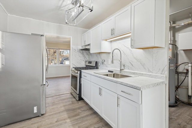 kitchen with a sink, stainless steel appliances, light countertops, light wood-style floors, and under cabinet range hood