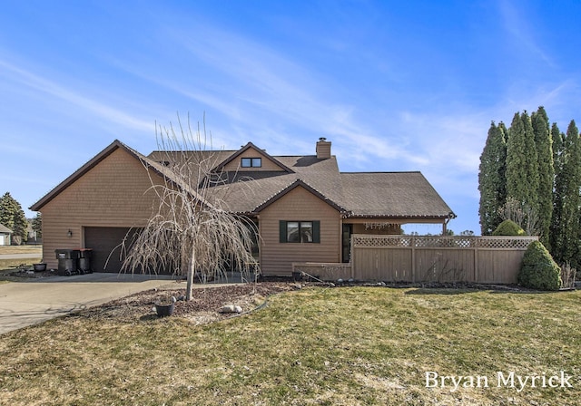 view of front of house with concrete driveway, fence, a garage, and a front yard