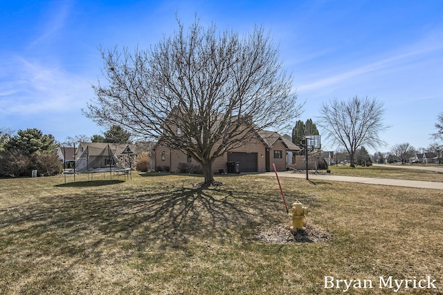 exterior space with a front lawn, a trampoline, a garage, and driveway