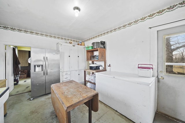 kitchen with open shelves, refrigerator, concrete floors, and stainless steel fridge with ice dispenser